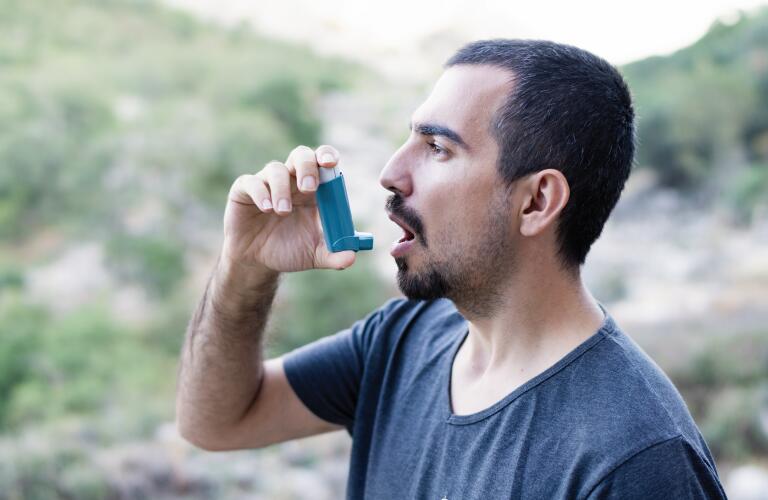 man outdoors using rescue inhaler