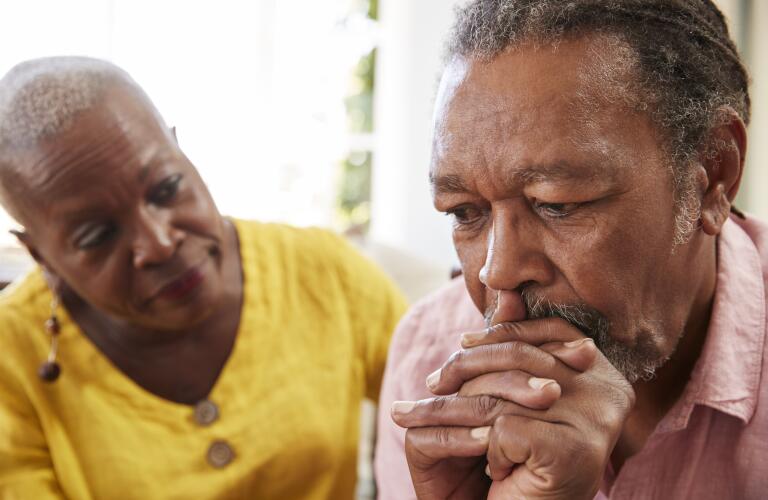 Senior African American man looking concerned while senior African American woman comfort hims 