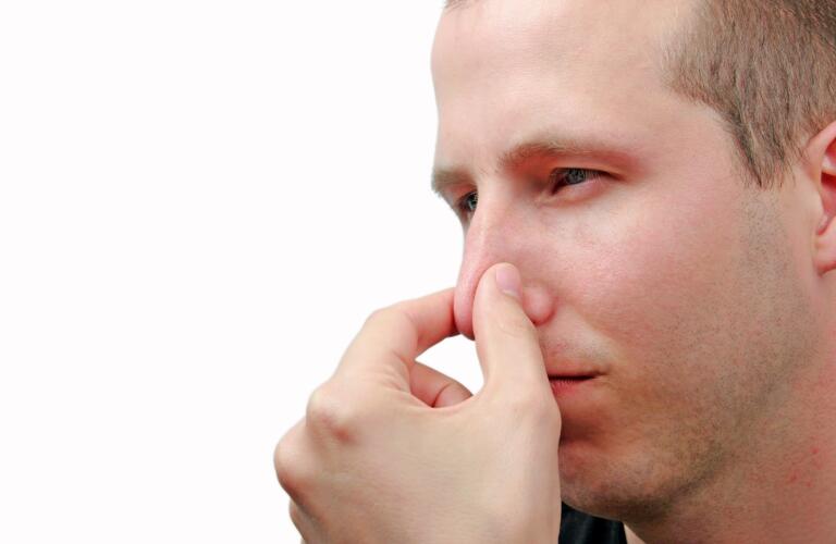 Young man holding nose with mouth closed