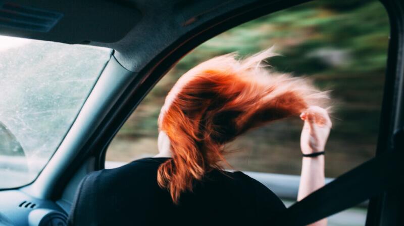 A woman with her head out of a car window