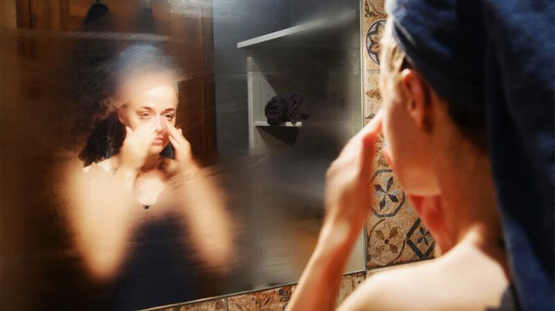 a woman is looking at her nose in the bathroom mirror