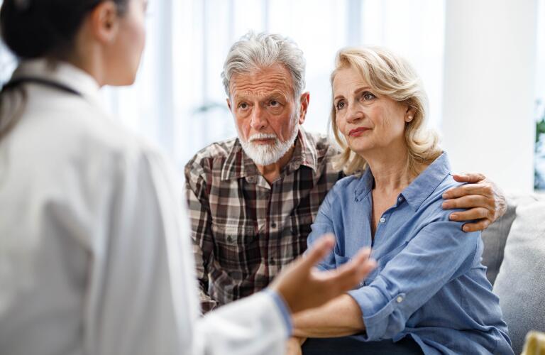 Mature couple talking to their doctor during her home visit.
