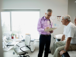 Doctor reviewing medical chart with senior man