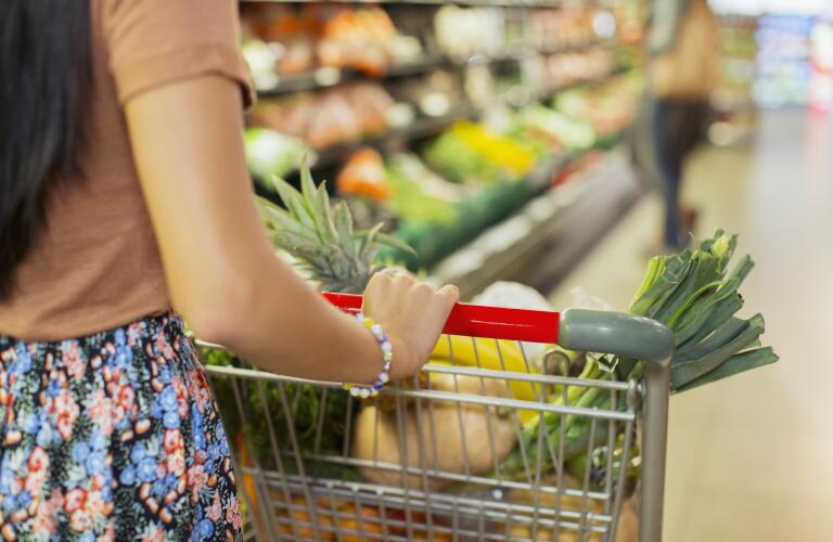 woman-pushing-cart-through-grocery-aisle