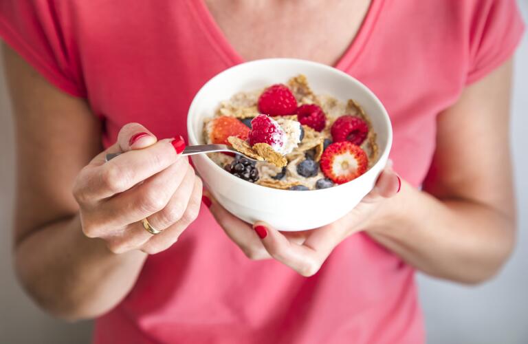 Close-up of Caucasian woman holding bowl of high-fiber cereal with berries