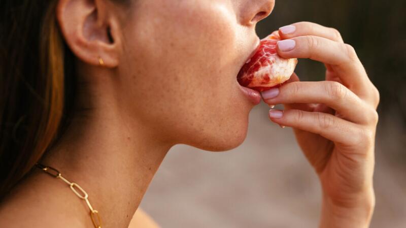 A woman is eating an orange.