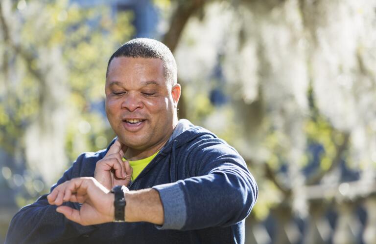 smiling middle age man checking pulse while exercising outside