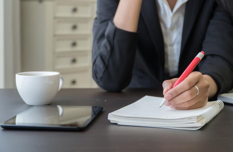 Cropped image of Caucasian woman writing in notebook on desk