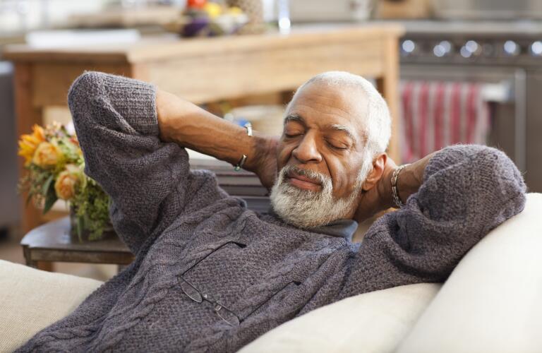 Older man relaxing on couch with eyes closed 