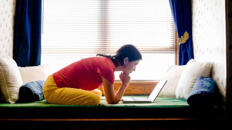 A woman is looking at a laptop screen.
