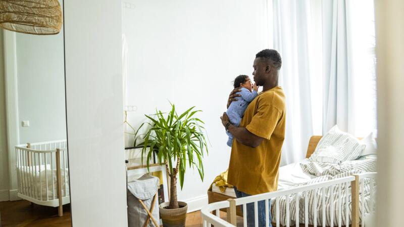 A father carrying his newborn at home