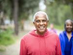 portrait of smiling African American senior man wearing red sweatshirt with partner in background