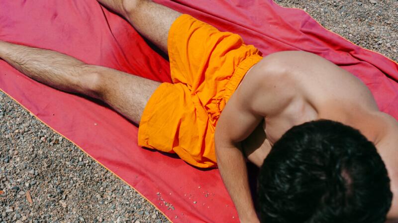 a man is relaxing at the beach wearing swim shorts