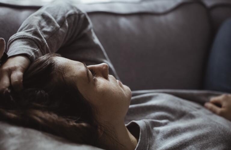 Close-up of sad woman lying on sofa at home