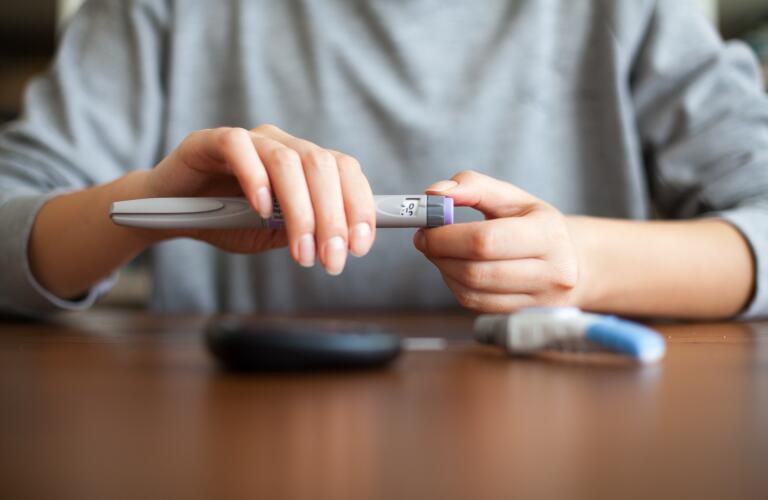 woman holding insulin pen at table