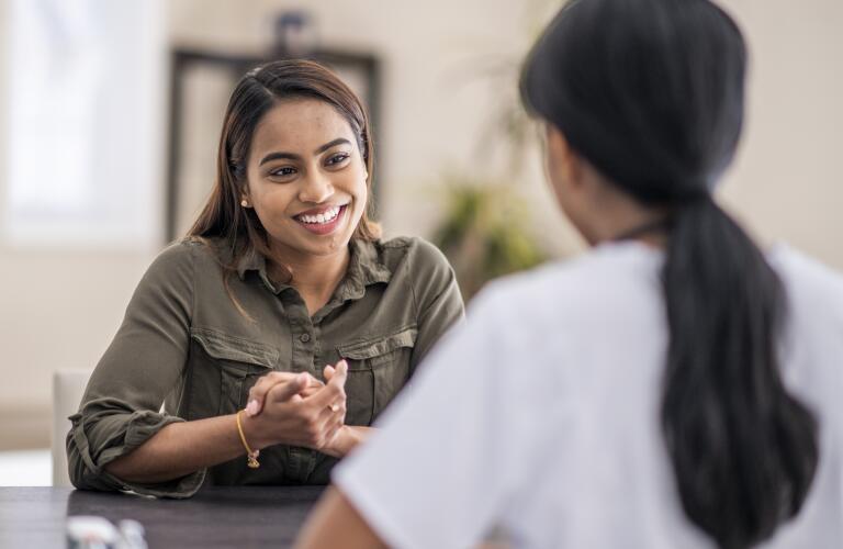 Young woman smiling and speaking to female doctor