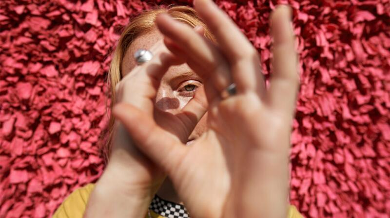 A woman pretends that her hands are a telescope and looks through them.