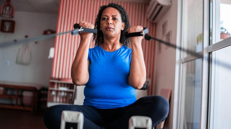 A woman doing bicep curls with a weight machine