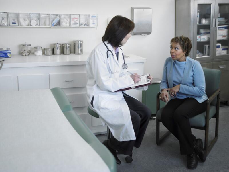 Female doctor talking to mature patient in examining room