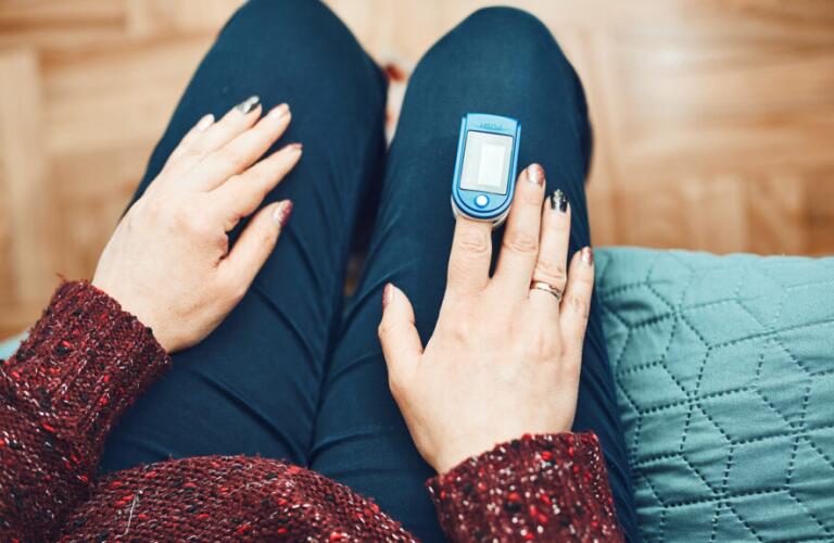 a person is sitting down and taking their pulse with a pulse oximeter
