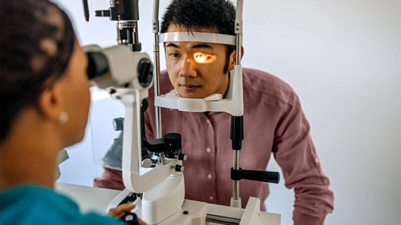 eye doctor looking at patient's eye with a slit lamp, which is a microscope