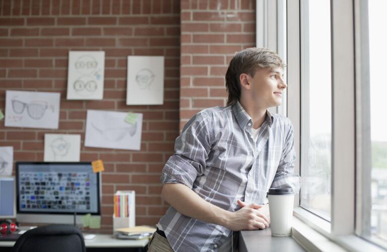 Young, male industrial designer gazing out window