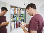 man looking at medication in front of medicine cabinet