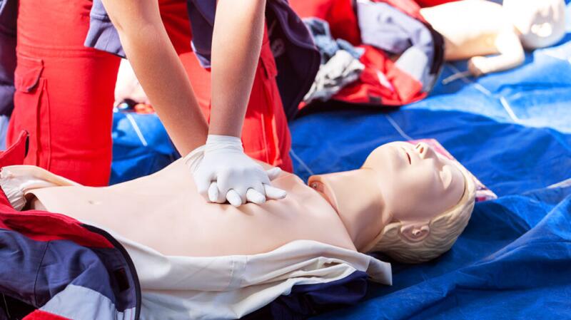A person performs chest compressions on a test doll