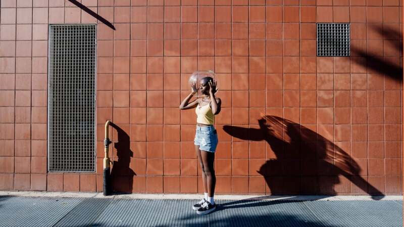 A person stands outside an urban area with a glass bubble over their head.