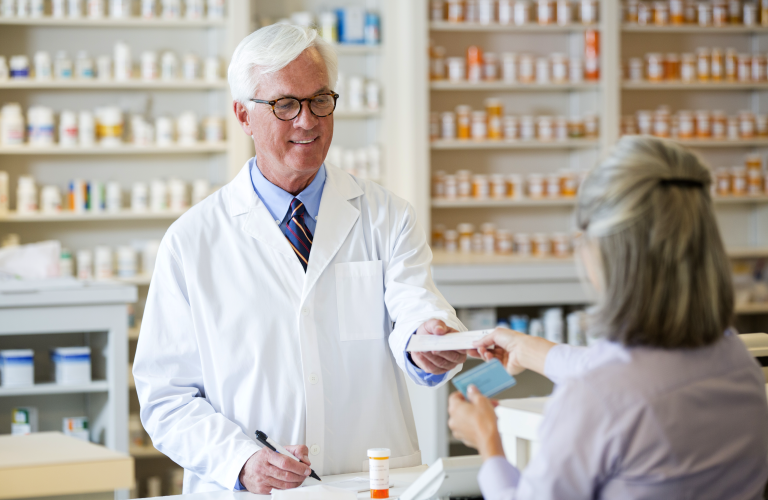 Caucasian pharmacist giving prescription to customer