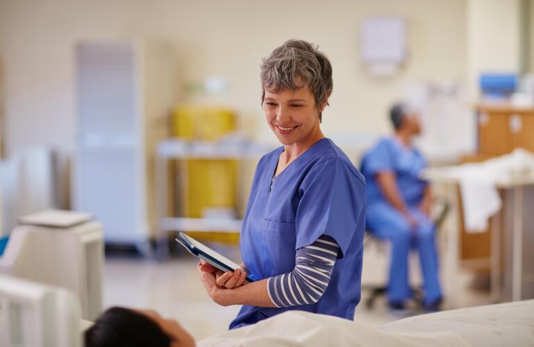 smiling nurse or doctor talking to patient before or after surgical recovery