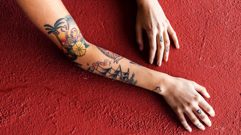 Tattooed arms against a textured wall