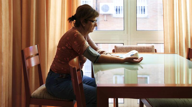 Woman checking blood pressure at kitchen table
