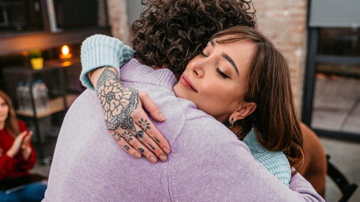 Woman with tattooed hands giving hug to unseen person