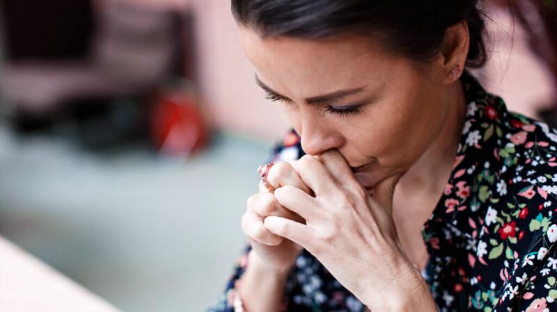woman looking down with her hands clasped