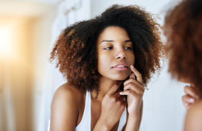 woman looking at face in mirror
