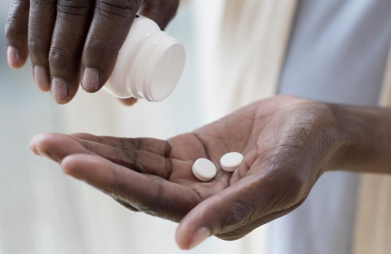 mature woman taking medication, round white pills