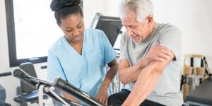 senior patient listening to his physical therapist teaching him the correct posture on the static bicycle 