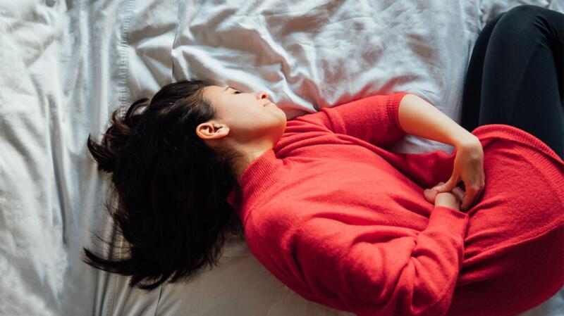 Women laying on her side holding her stomach