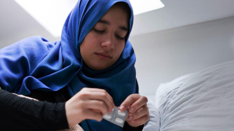 Older teenager taking medication from pill packet