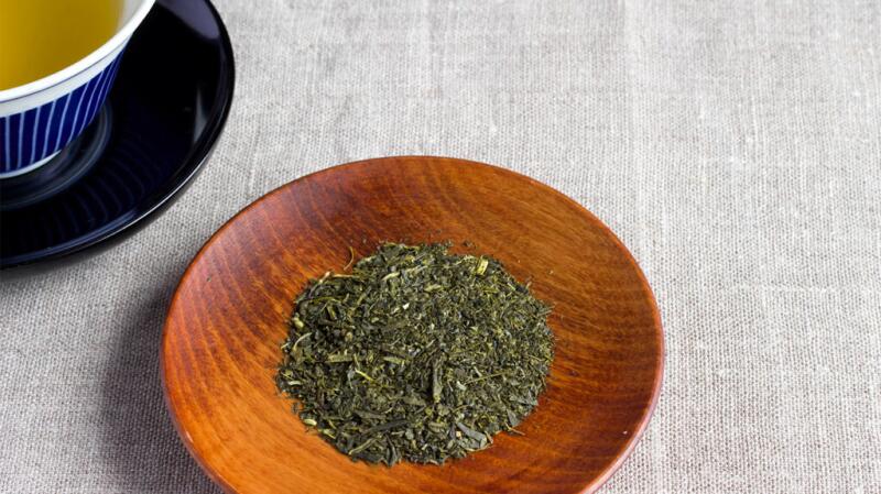 there are green tea leaves on a wooden bowl