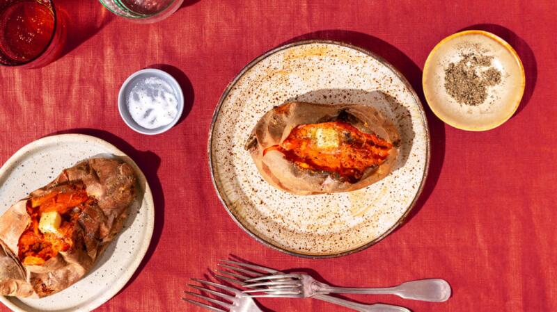 Sweet potatoes on plates are on a red tablecloth.