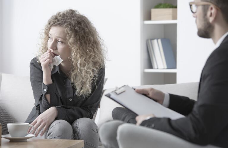 Young Caucasian woman crying and staring while talking to counselor or therapist