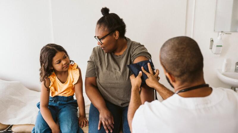 Female having blood pressure checked with child watching.