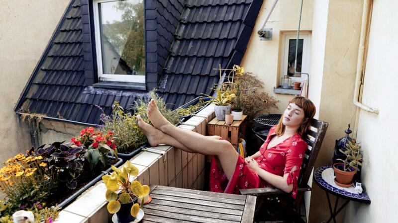 Young woman relaxing on outdoor patio with legs up on brick wall