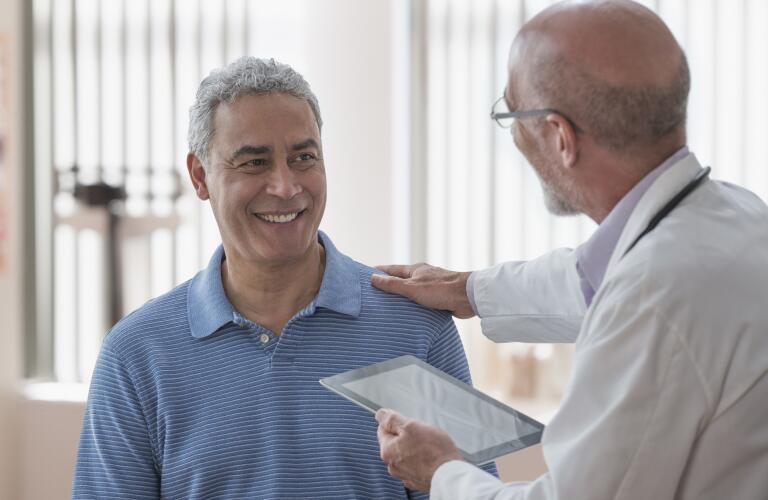 smiling-man-speaking-with-doctor-holding-tablet