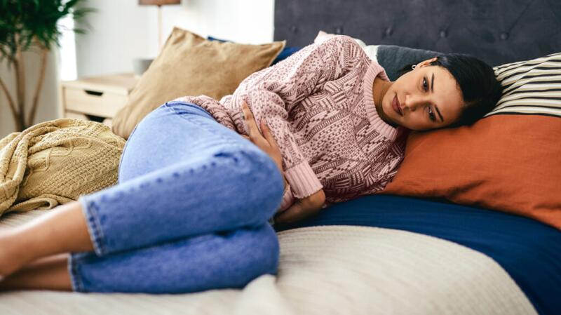 A woman lying in bed holding her lower stomach