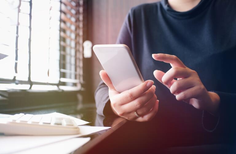 midsection view of woman using smartphone and calculator
