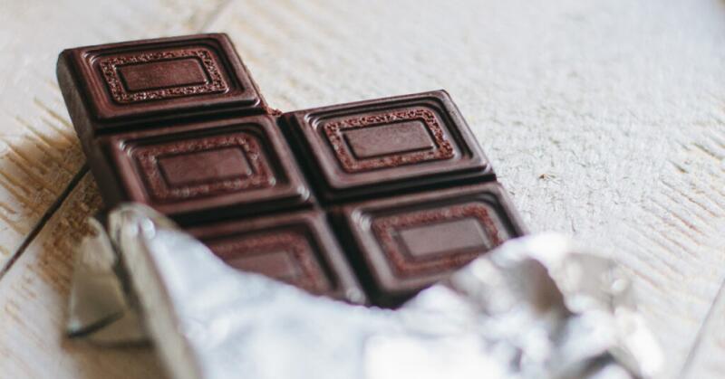 A partially unwrapped bar of plain dark chocolate.
