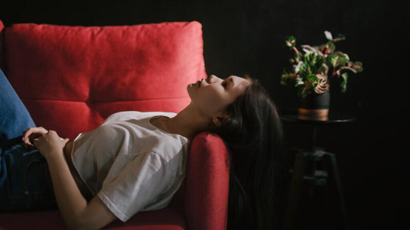 A woman resting on a couch with her hands on her stomach